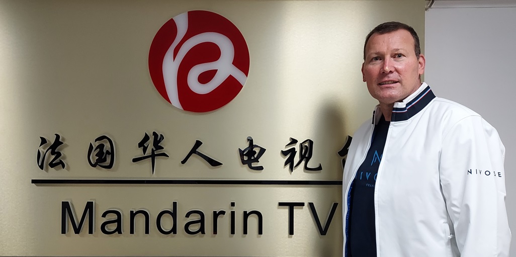 Eric Monnin devant le logo de MandarinTV